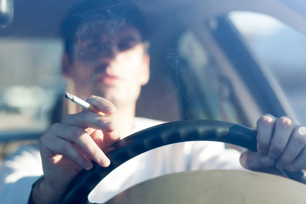 Uomo che fuma all'interno di un automobile